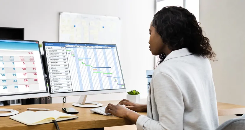 Professional managing schedules and project timelines on dual monitors, representing project management skills and organization.