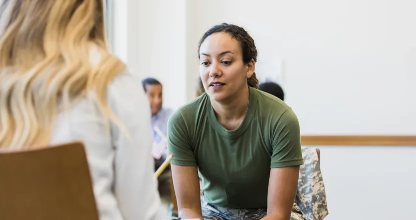 Military service member in uniform having a focused conversation with a counselor or advisor, discussing support and opportunities.