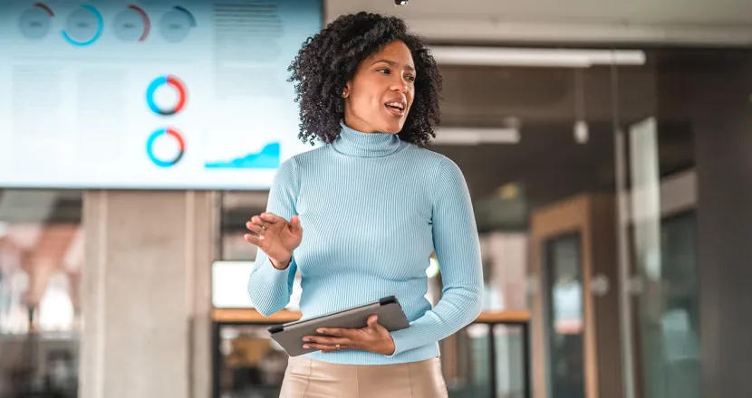 A confident business professional presents data during a meeting, demonstrating leadership and analytical skills gained through an MBA.