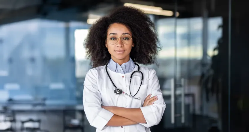 Nurse practitioner student smiling with arms crossed, wearing a white coat