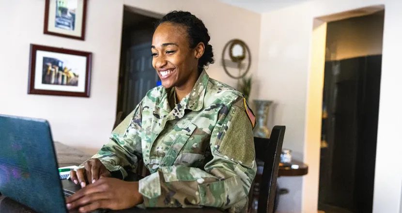 Herzing University military student in uniform studying online at home, representing Associate of Science in Interdisciplinary Studies program for servicemembers