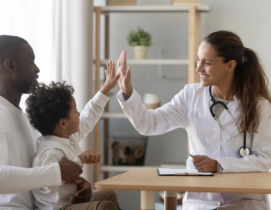 Family nurse practitioner high fiving pediatric patient in office during appointment