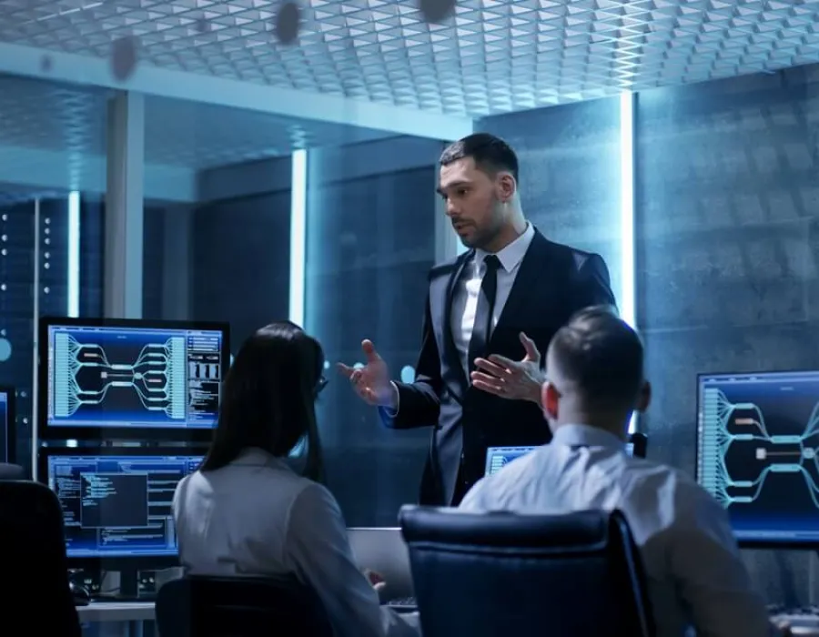 IT manager wearing a suit leading team meeting at desk