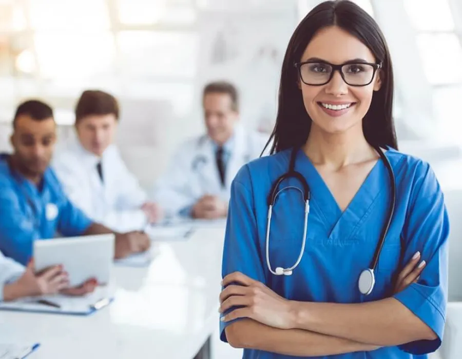 Neuroscience nurse in blue scrubs smiling in hospital room