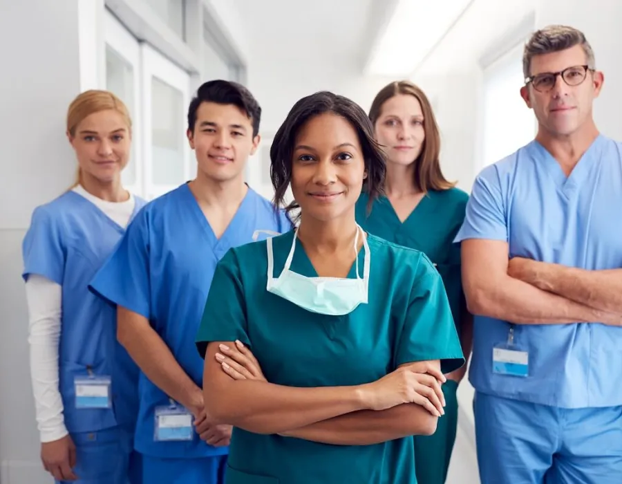 Team of nurses and healthcare staff smiling in hospital corridor