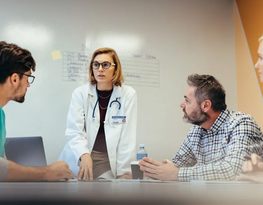 Healthcare leadership team discussing hospital needs with whiteboard in background