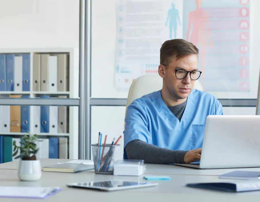 Medical office assistant working at front desk awaiting patients for appointments