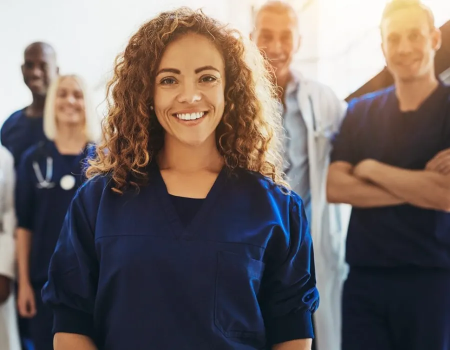 Nursing student who was formerly a medical assistant smiling in group photo with healthcare staff