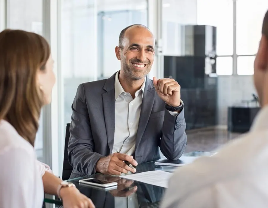 Accountant leaning on desk speaking with clients during meeting