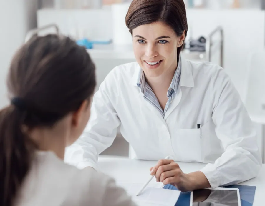 Adult-Gerontology Nurse Practitioner (AGNP) discussing treatment plan with patient and smiling