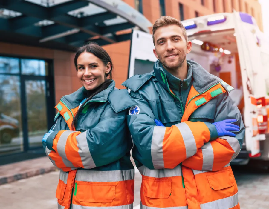 Emergency Medical Technicians Smiling Standing Besides Ambulance