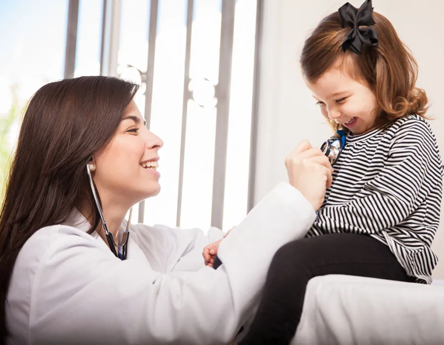 Pediatric Nurse Practitioner Smiling with Young Patient Reading Heart Rate with Stethoscope