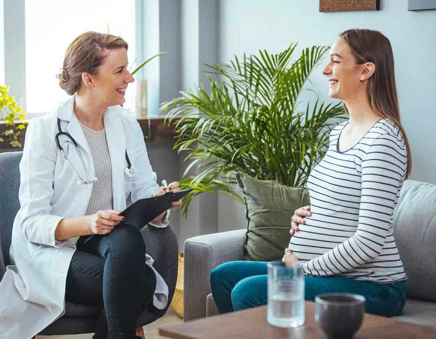 Women's health nurse practitioner smiling with pregnant patient