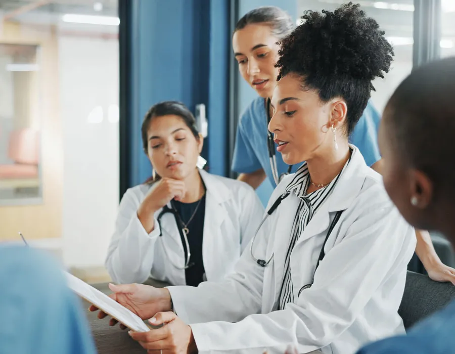 Healthcare manager in white coat leading team discussion in hospital conference room