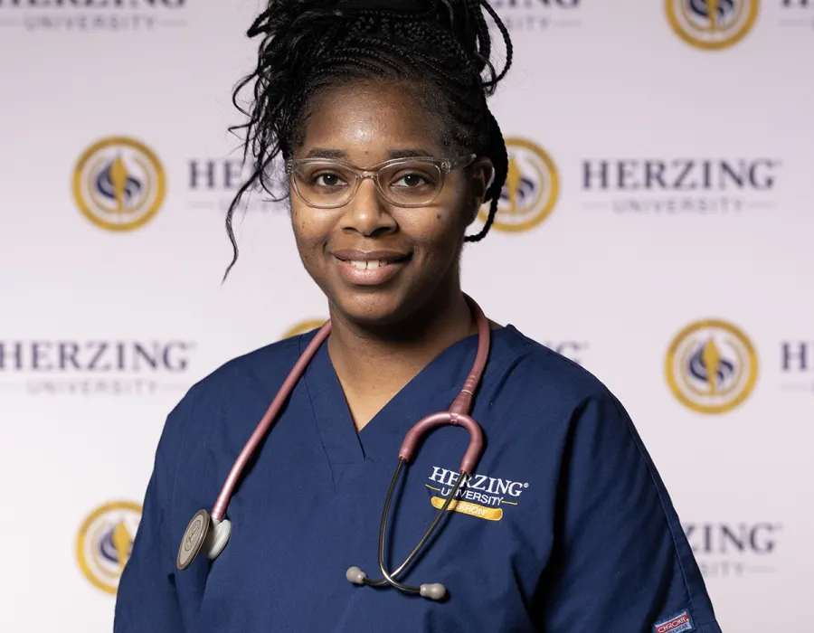 Herzing nursing student in blue scrubs wearing stethoscope smiling for portrait photo