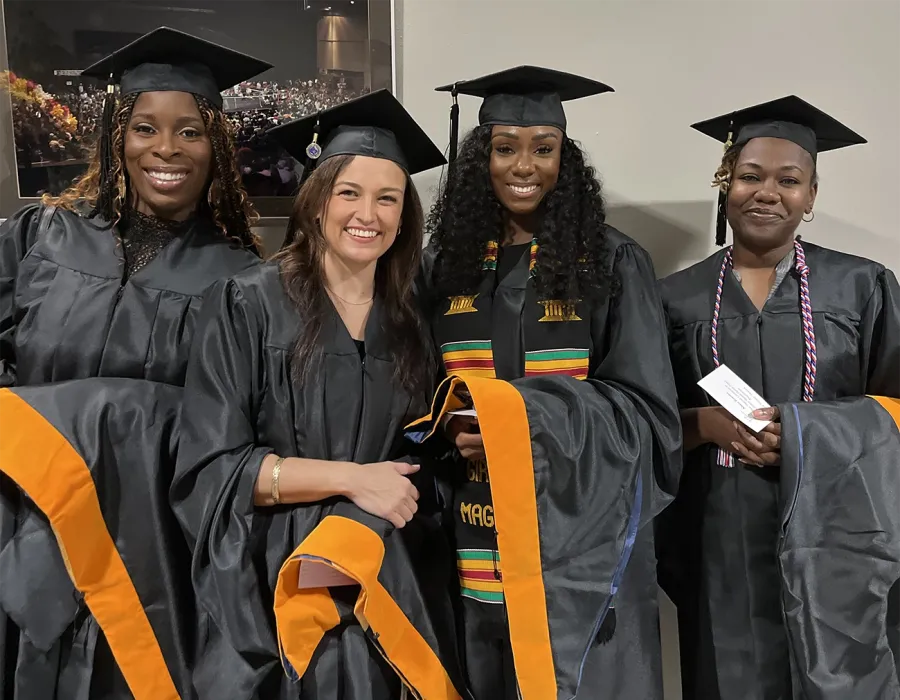 Several Herzing University nursing graduates smiling at graduation ceremony in black gowns