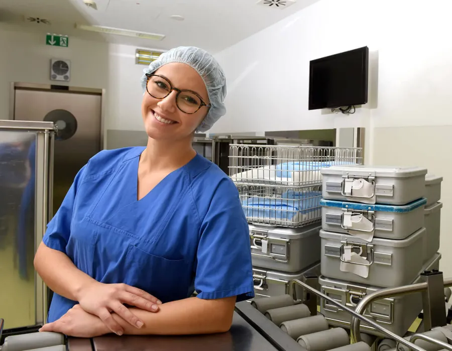 Sterile processing technician in lab wearing PPE posing and smiling for photo