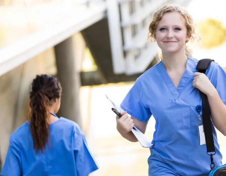 Smiling nursing student in scrubs walking to class