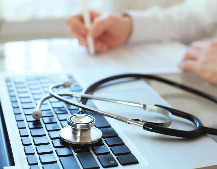 Health Information Management Professional Taking Notes by Laptop with Stethoscope