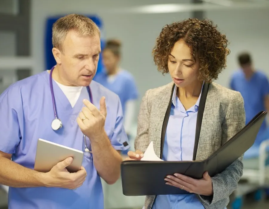 Healthcare manager reviewing meeting notes with registered nurse in hospital