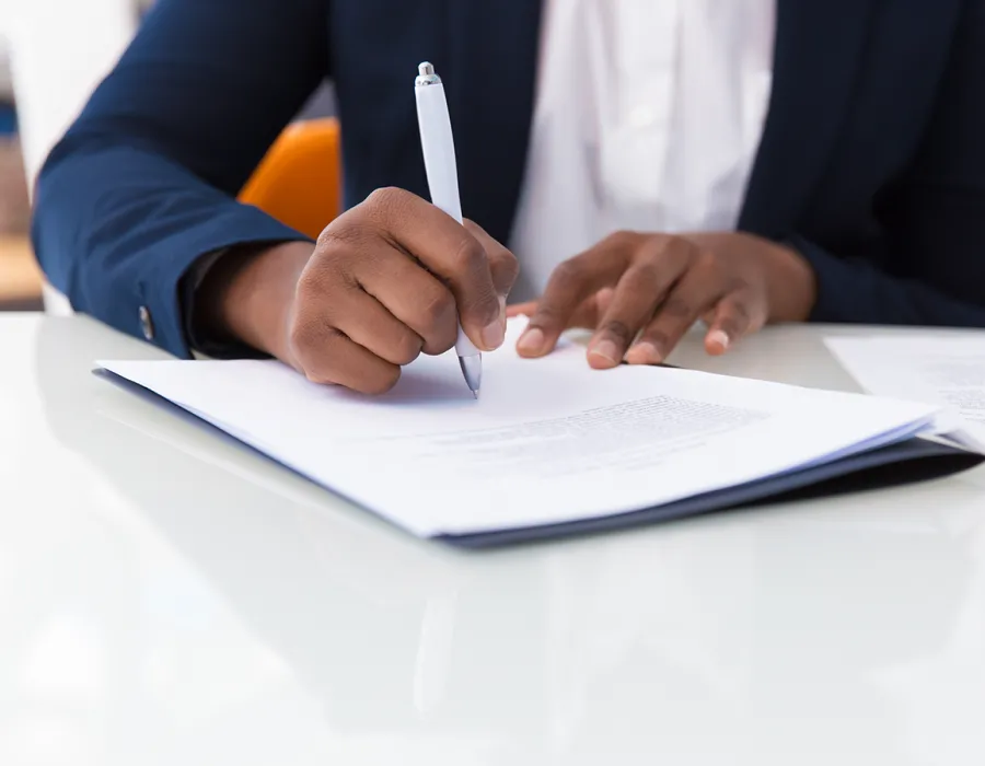 Paralegal seated at desk taking notes with pen and paper