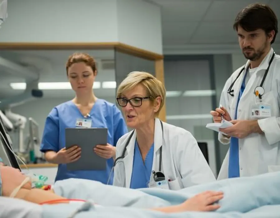 Family nurse practitioner seated at bedside with patient while nurses observe in hospital room