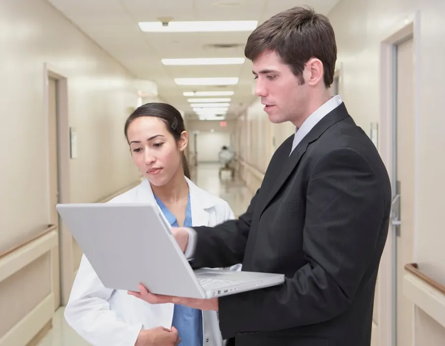 Healthcare manager reviewing documents with nurse administrator in hospital hallway