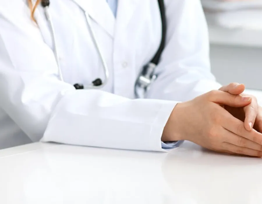 Healthcare manager with hands rested on desk speaking to team during meeting