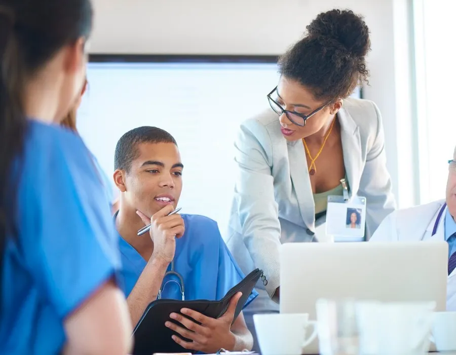 Nurse administrator speaking with other healthcare managers during team meeting