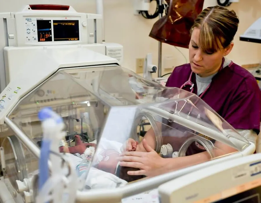 Neonatal nurse comforting infant in NICU