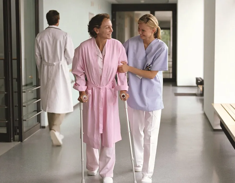 Occupational therapist helping patient walk on crutches