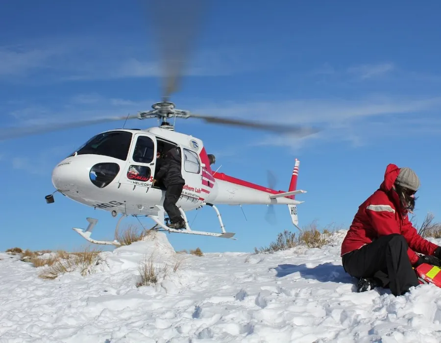 Flight nurse administering treatment in the field with helicopter in the background