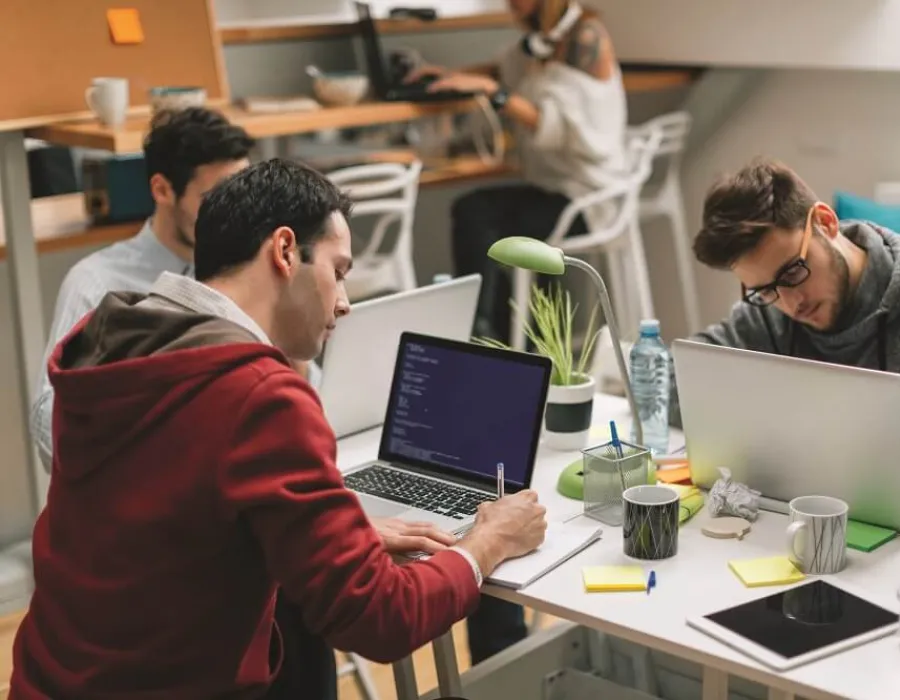 Software developers seated around table with laptops collaborating on project