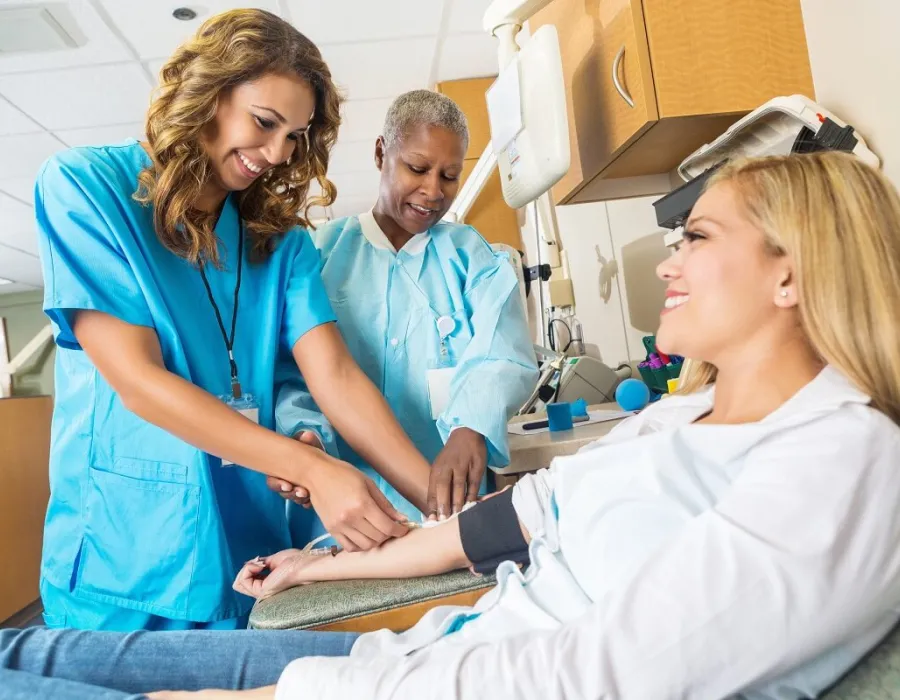 Nursing student learning how to draw blood in lab simulation with nurse teacher