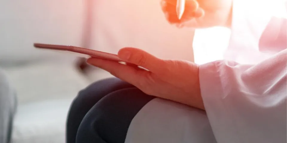 PMHNP holding tablet during patient appointment taking notes