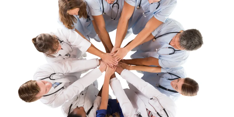 Group of medical professionals in a huddle with their hands stacked in the middle