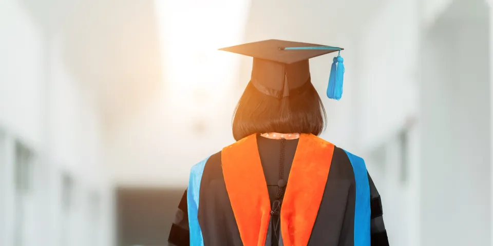 PhD student with their back facing viewer wearing an orange nursing hood