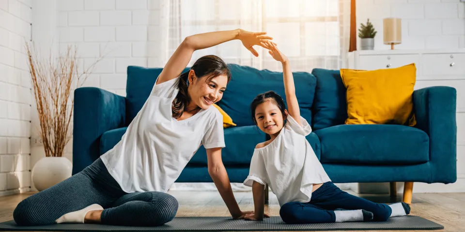 A mother coaches her little daughter in yoga creating a family bond filled with happiness relaxation and togetherness.