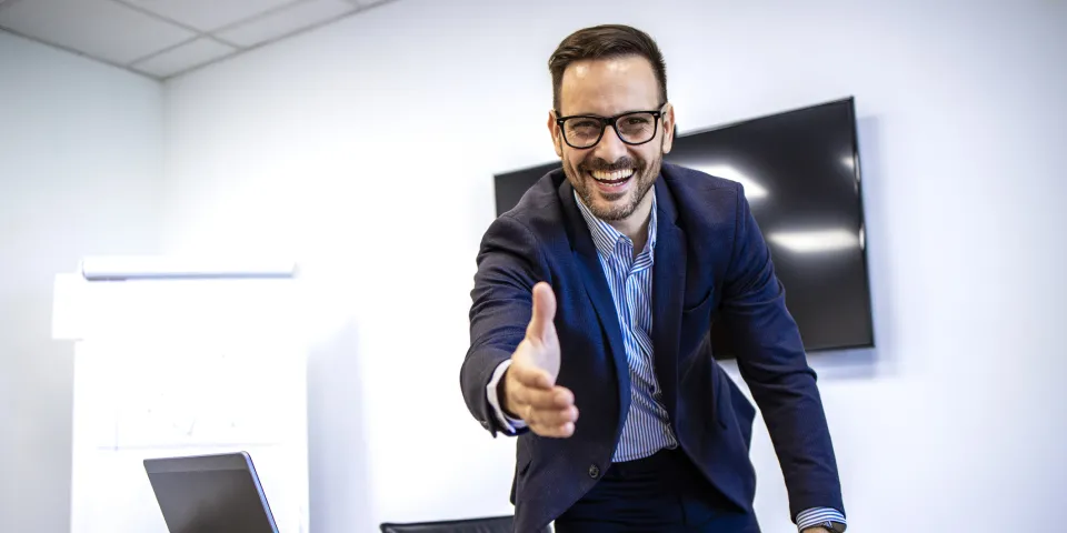 Portrait of businessman in elegant suit showing welcoming hand to the new employees.