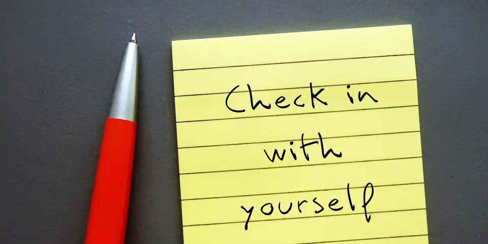 Note paper on gray background with handwritten text - Check in with yourself - carving out time each day to ask yourself how you're doing