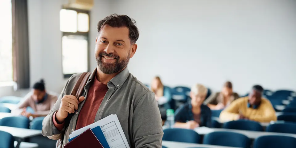 Happy mature man attending adult education training course and looking at camera.