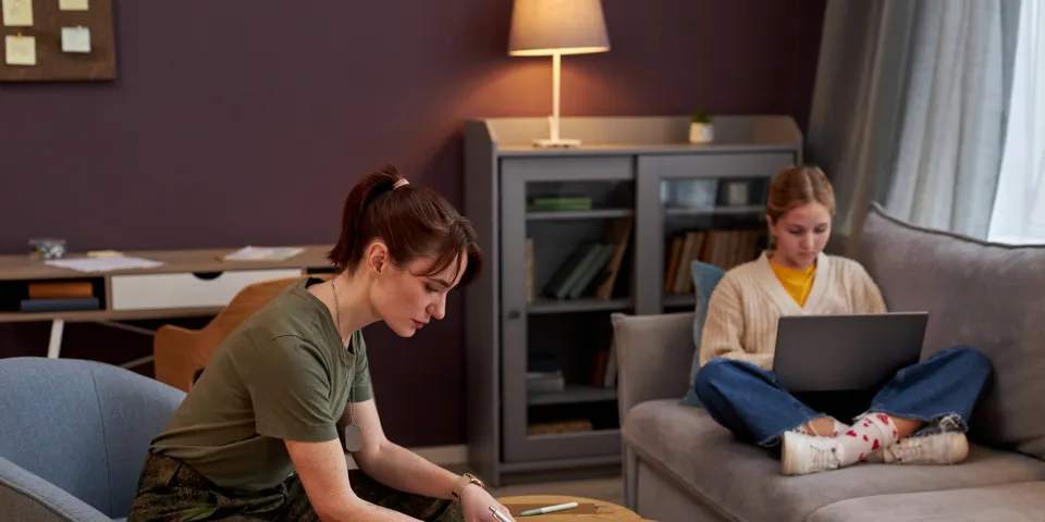 Side view portrait of young military woman working with documents at home, daughter in background, copy space