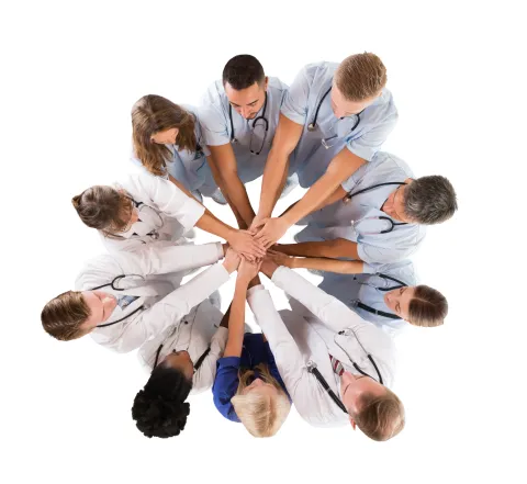 Group of medical professionals in a huddle with their hands stacked in the middle